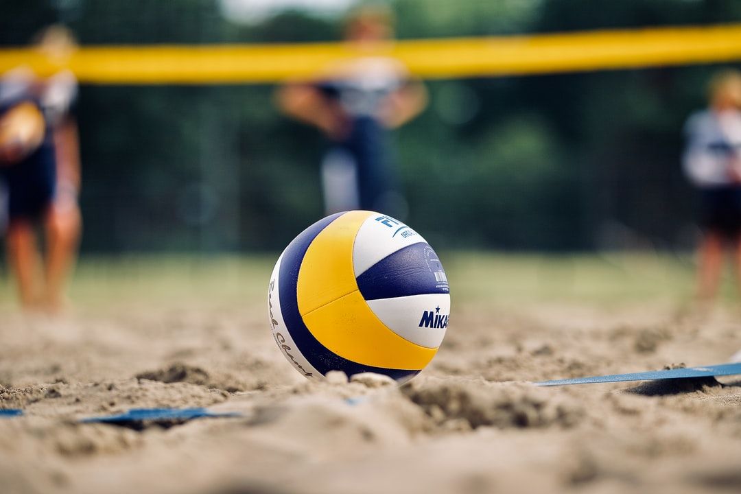 yellow and white volleyball on brown sand during daytime