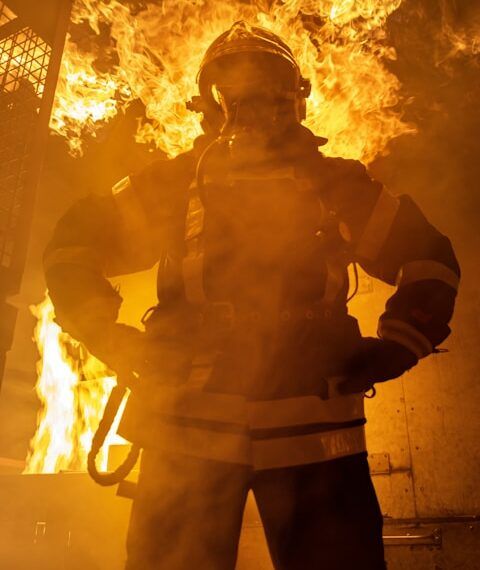 a firefighter standing in front of a large fire